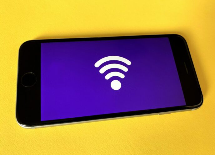 a close up image of a cellphone whose screen is blank save a large, bright wifi symbol in the center on a dark purple background